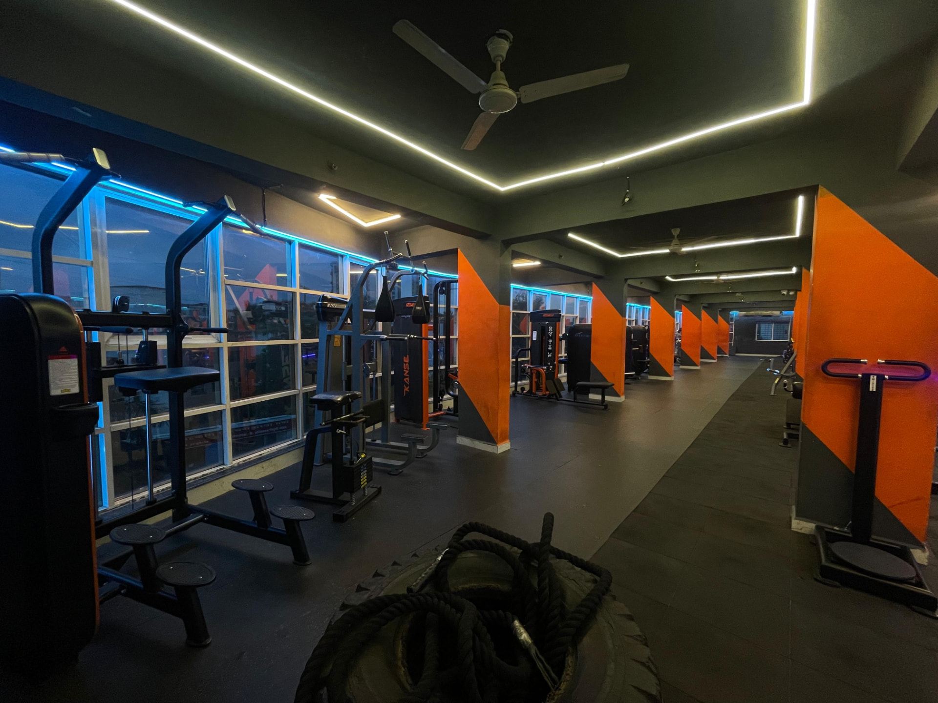 Long row of pin-loaded weight machines along the windowed wall at SK Fitness Gym, Kharadi Road, Pune