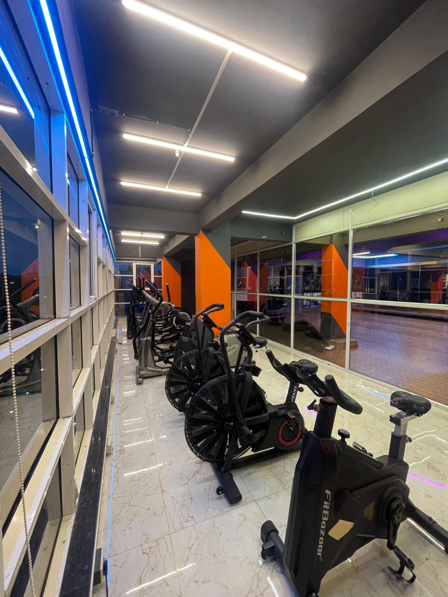 Spin bikes and air bikes beside the window in the cardio zone of SK Fitness Gym Kharadi, Pune